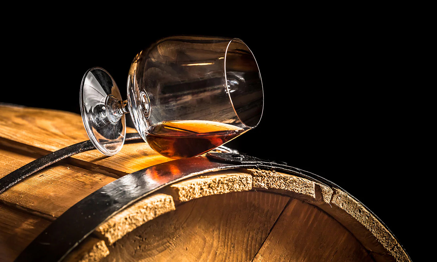Verre d'Armagnac sur une barrique